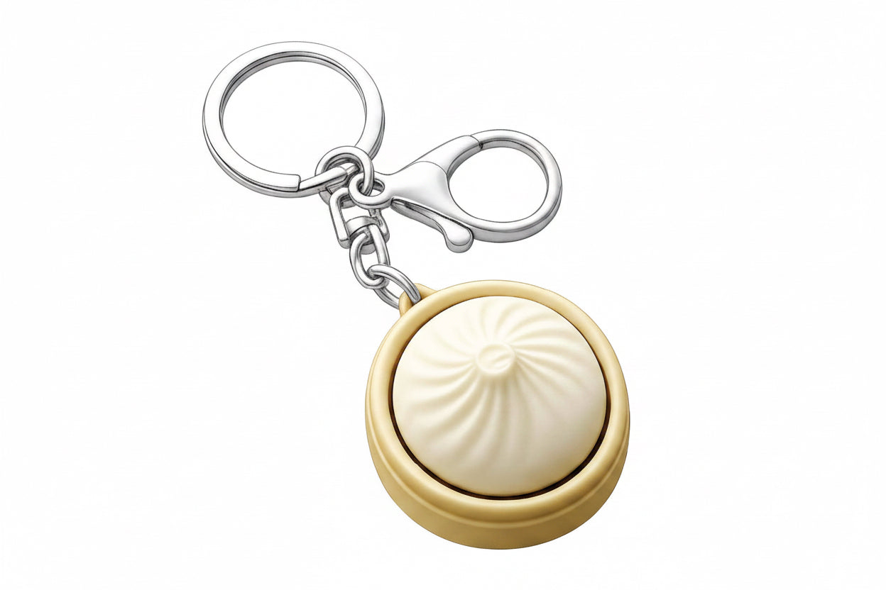 Gold and silver keychain with a round beige object on a white background