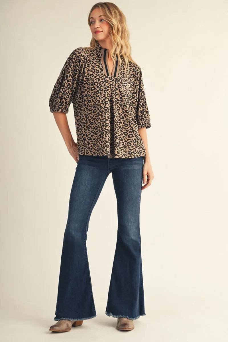 Women's leopard print notched V-neck blouse with contrast ribbed collar and puff sleeves styled with flare jeans