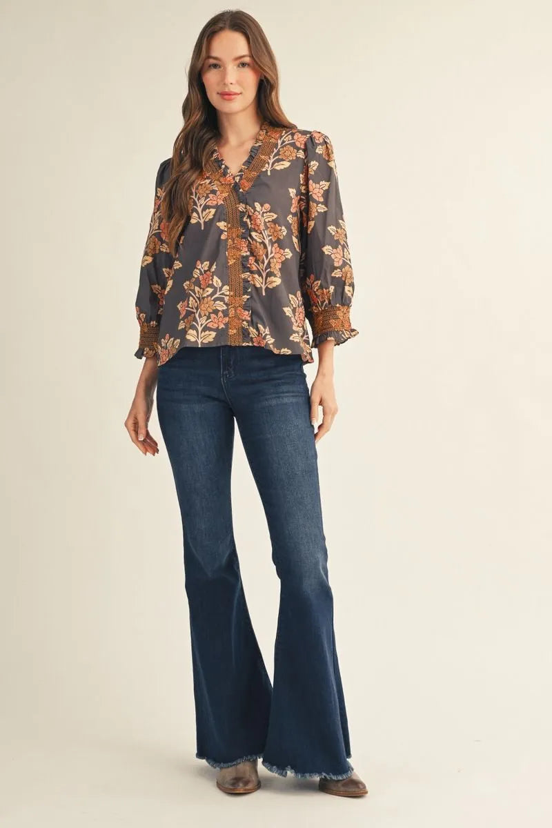 Women's fall floral puff sleeve blouse styled with dark wash flare jeans and boots