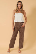 A woman modeling a white strapless tube top and Women’s high rise straight leg stretch washed pants in mocha brown