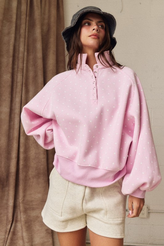 Oversized pink polka dot pullover with ribbed cuffs and snap-up collar for spring fashion.