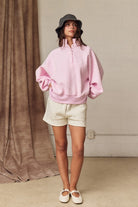 Oversized pink polka dot pullover with ribbed cuffs and snap-up collar for spring fashion.