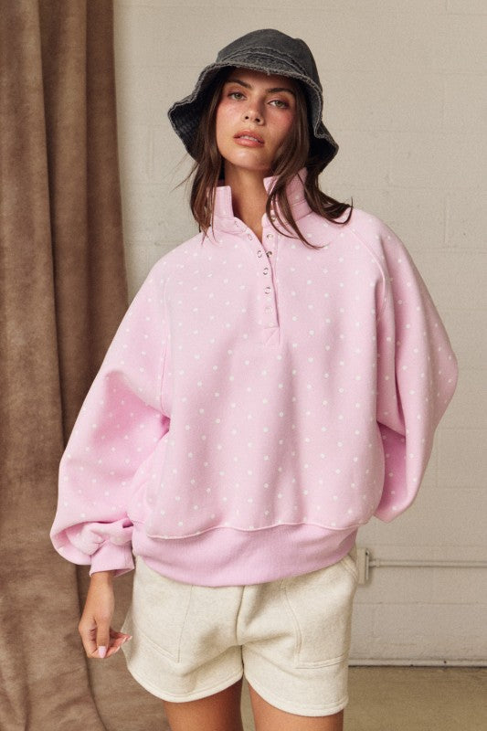 Oversized pink polka dot pullover with ribbed cuffs and snap-up collar for spring fashion.