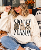 Cozy Spooky Season ghost graphic sweatshirt styled with distressed jeans and an olive green baseball cap, perfect for pumpkin patch outings.