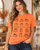Orange tee with black pumpkin graphics and 'pumpkin season' script, worn by a woman.