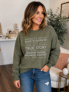 Woman wearing an olive green Rooted in Christ Christian faith graphic crewneck sweatshirt with jeans.
