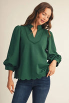 Women's emerald green notched V-neck top with scalloped neckline detail and puff sleeves