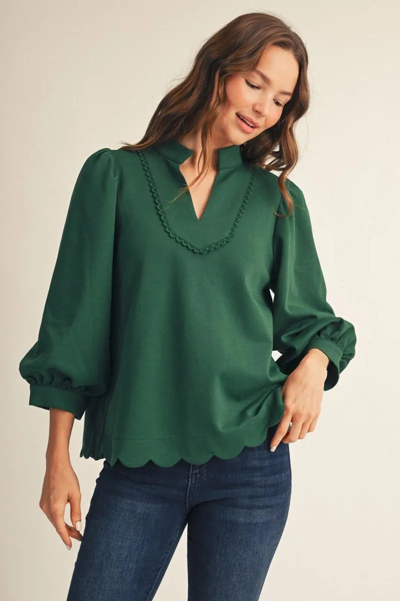 Women's emerald green notched V-neck top with scalloped neckline detail and puff sleeves