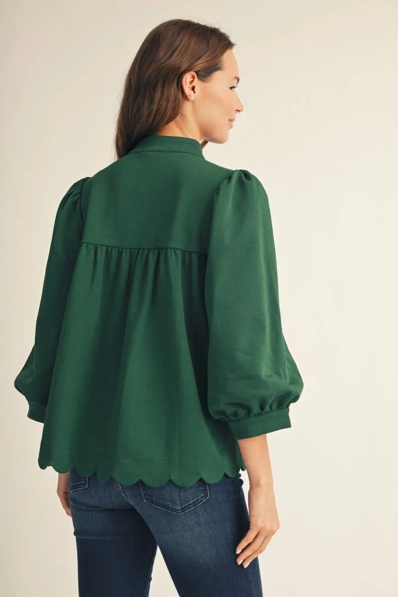 Back of emerald green blouse showing gathered back yoke, puff sleeves and scalloped hem